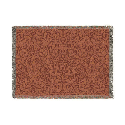 A woven cotton blanket with a floral William Morris & Co geometric pattern in a rust colour, featuring a colourful fringed edge.