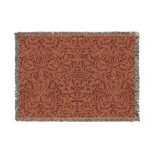 A woven cotton blanket with a floral William Morris & Co geometric pattern in a rust colour, featuring a colourful fringed edge.