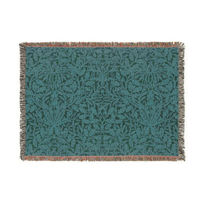 A woven cotton blanket with a William Morris & Co floral geometric pattern in teal colour, featuring a fringe.