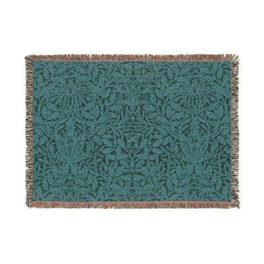 A woven cotton blanket with a William Morris & Co floral geometric pattern in teal colour, featuring a fringe.