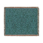 A woven cotton blanket with a geometric pattern in teal color, featuring a fringe.