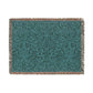 A woven cotton blanket with a geometric pattern in teal color, featuring a fringe.