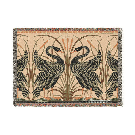 A woven cotton blanket with a geometric William Morris & Co pattern featuring birds, in beige, black, and green colours, with fringed edges.