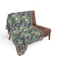 Floral patterned blanket draped over a brown chair on a white background