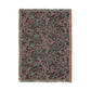 A rectangular woven throw blanket with fringe on all sides, featuring an intricate floral and scroll pattern in muted dusty pink, teal blue, and gray on a dark charcoal background.