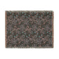 A rectangular woven throw blanket with fringed edges, featuring an abstract pattern in dusty pink, teal blue, and light gray on a dark charcoal background.