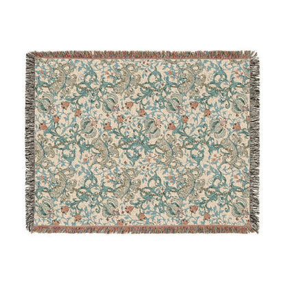 A rectangular woven throw blanket with a cream background and an intricate paisley pattern in teal, brown, and gray, finished with fringed edges.
