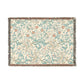 A rectangular woven throw blanket with a dense floral and vine pattern in soft teal, dusty pink, and beige on an off-white background, finished with fringed edges.