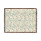 A rectangular woven throw blanket with a cream background and an intricate floral pattern in teal, rust orange, and beige. The blanket features fringed edges on all sides.