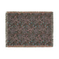 A rectangular woven throw blanket with fringed edges, featuring an intricate abstract floral pattern in muted pink, teal blue, and light gray on a dark charcoal background.