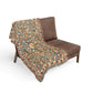 Decorative blanket with floral pattern draped over a brown chair on a white background