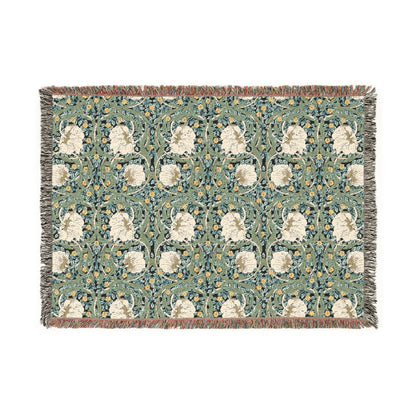 A woven cotton blanket with a green and William Morris & Co floral pattern, featuring a colourful fringed edge.
