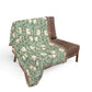 Floral patterned throw blanket draped over a brown chair on a white background