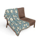 Floral patterned throw blanket draped over a brown chair on a white background