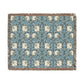 A woven cotton blanket with a geometric pattern in shades of blue and beige, featuring colorful fringed edges.