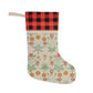 A Christmas stocking with a floral William Morris & Co pattern in red and green colours, featuring a red and black checkered cuff at the top.