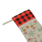 A Christmas stocking with a floral William Morris & Co pattern in red and green colours, featuring a red and black checkered cuff at the top.