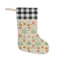 A Christmas stocking with a floral pattern in red and green colors, featuring a red and black checkered cuff at the top.