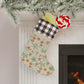 A Christmas stocking with a floral William Morris & Co pattern in red and green colours, featuring a red and black checkered cuff at the top.