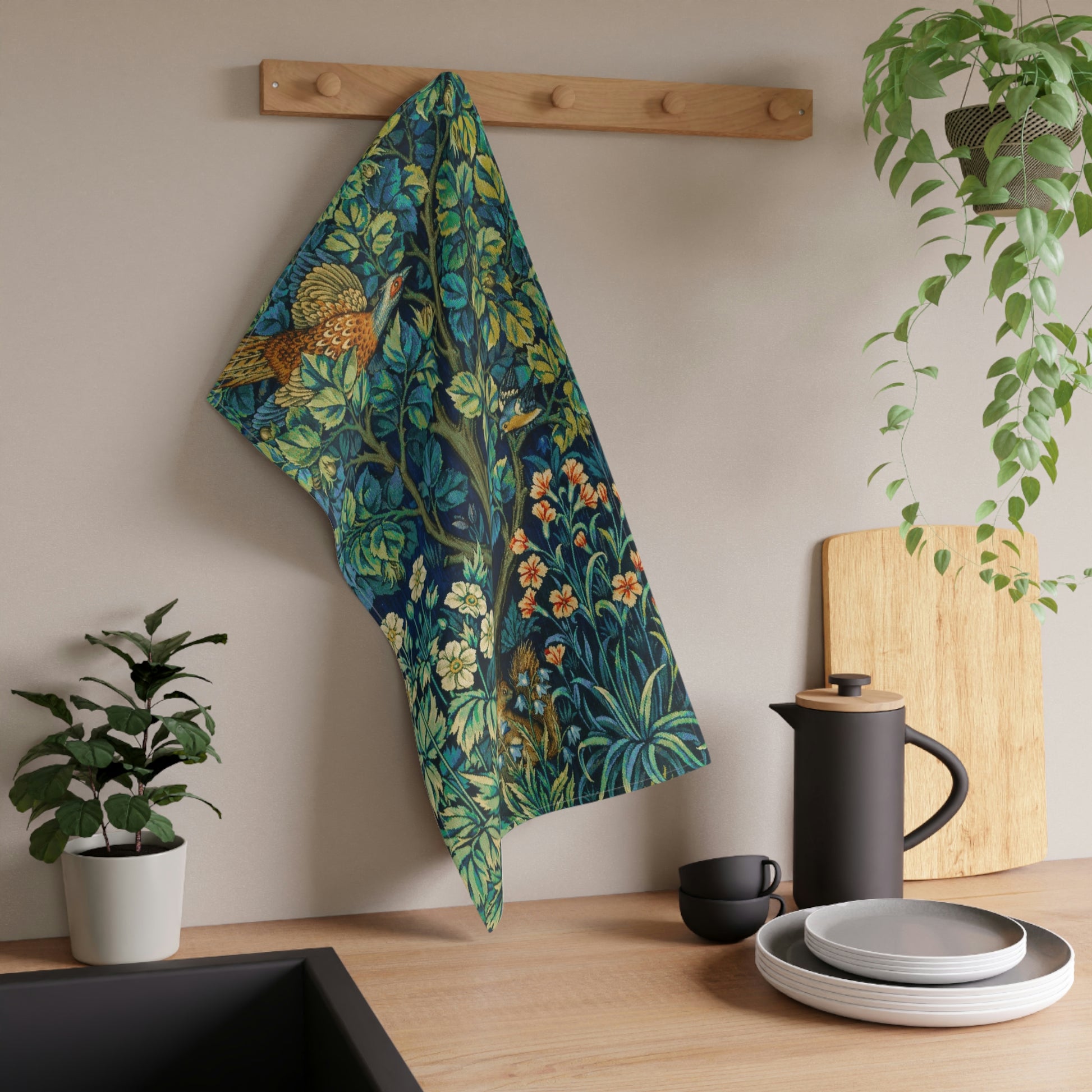 A kitchen tea towel featuring an artistic design with pheasants, squirrels, and floral elements on a blue background.
