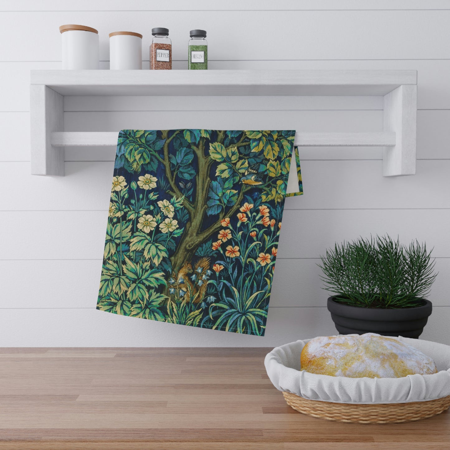 A kitchen tea towel featuring an artistic design with pheasants, squirrels, and floral elements on a blue background.