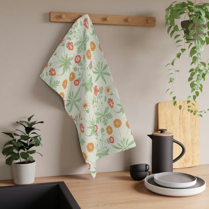 A kitchen tea towel featuring a floral William Morris & Co pattern with prominent orange and green colours on a white background.