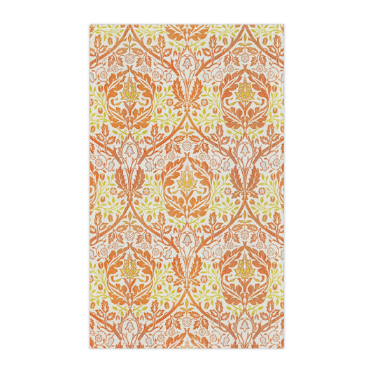 A kitchen tea towel with a floral William Morris  & Co pattern in orange, green, and yellow colours on a light background. 