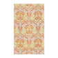 A kitchen tea towel with a floral William Morris  & Co pattern in orange, green, and yellow colours on a light background. 