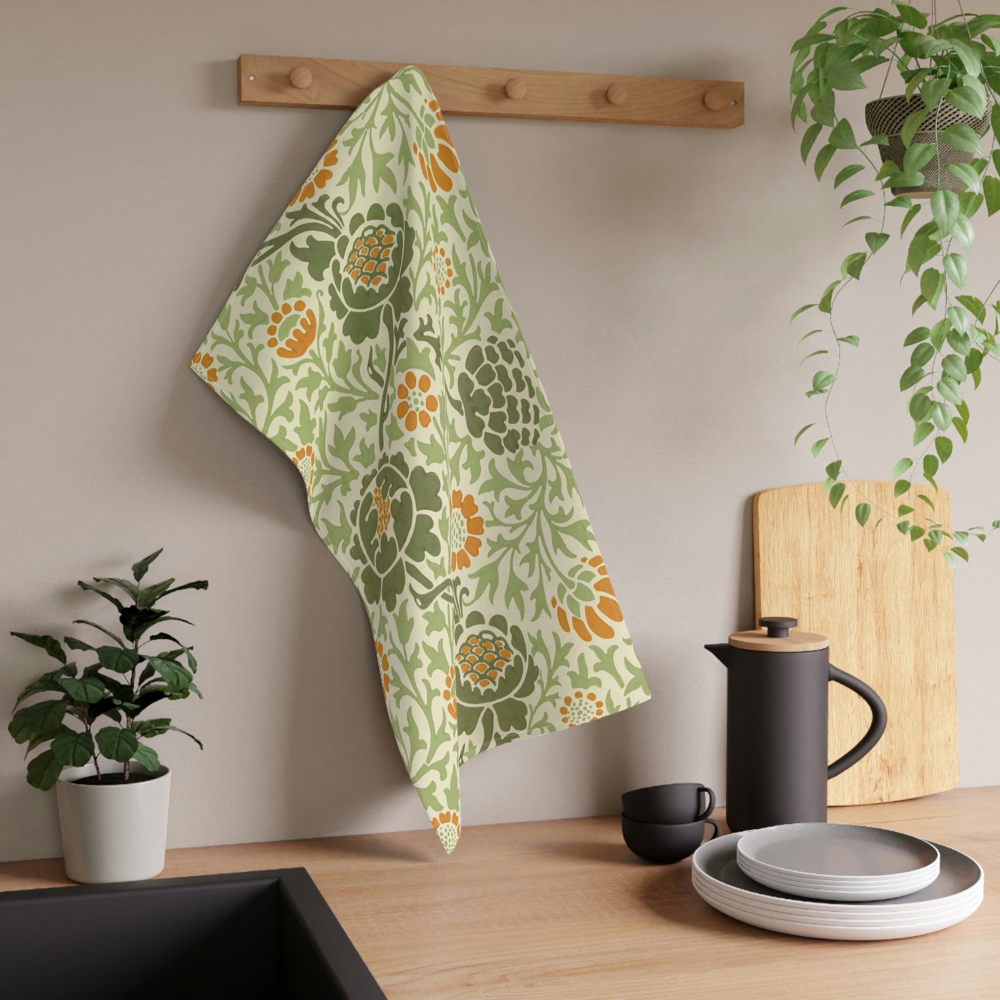 A kitchen tea towel with a floral William Morris & Co pattern featuring green, orange and yellow colours on a light background.