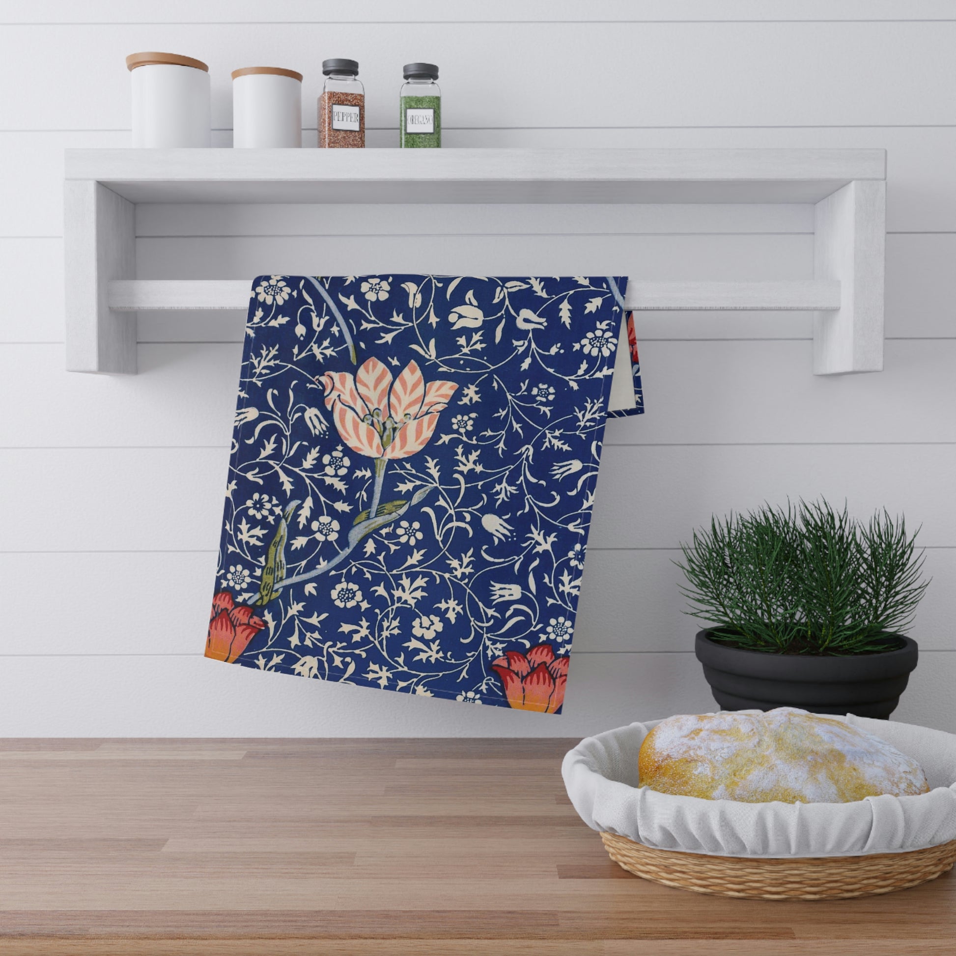 A kitchen tea towel with a blue background featuring William Morris & Co floral and geometric Art Nouveau patterns.