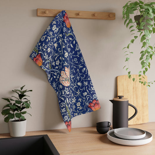 A kitchen tea towel with a blue background featuring William Morris & Co floral and geometric Art Nouveau patterns.