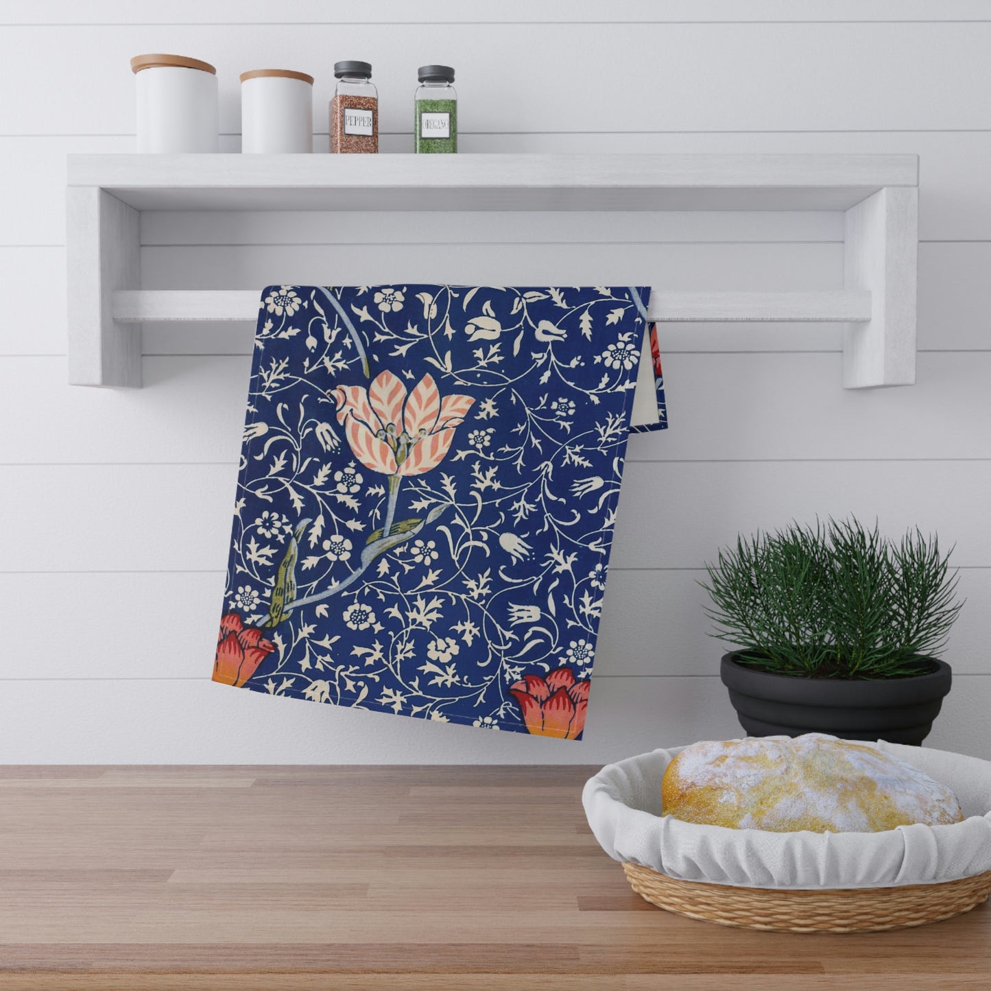 A kitchen tea towel with a blue background featuring William Morris & Co floral and geometric Art Nouveau patterns.
