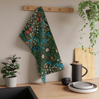 A kitchen tea towel with a floral pattern inspired by William Morris, featuring tulips in red and blue on a dark green background.