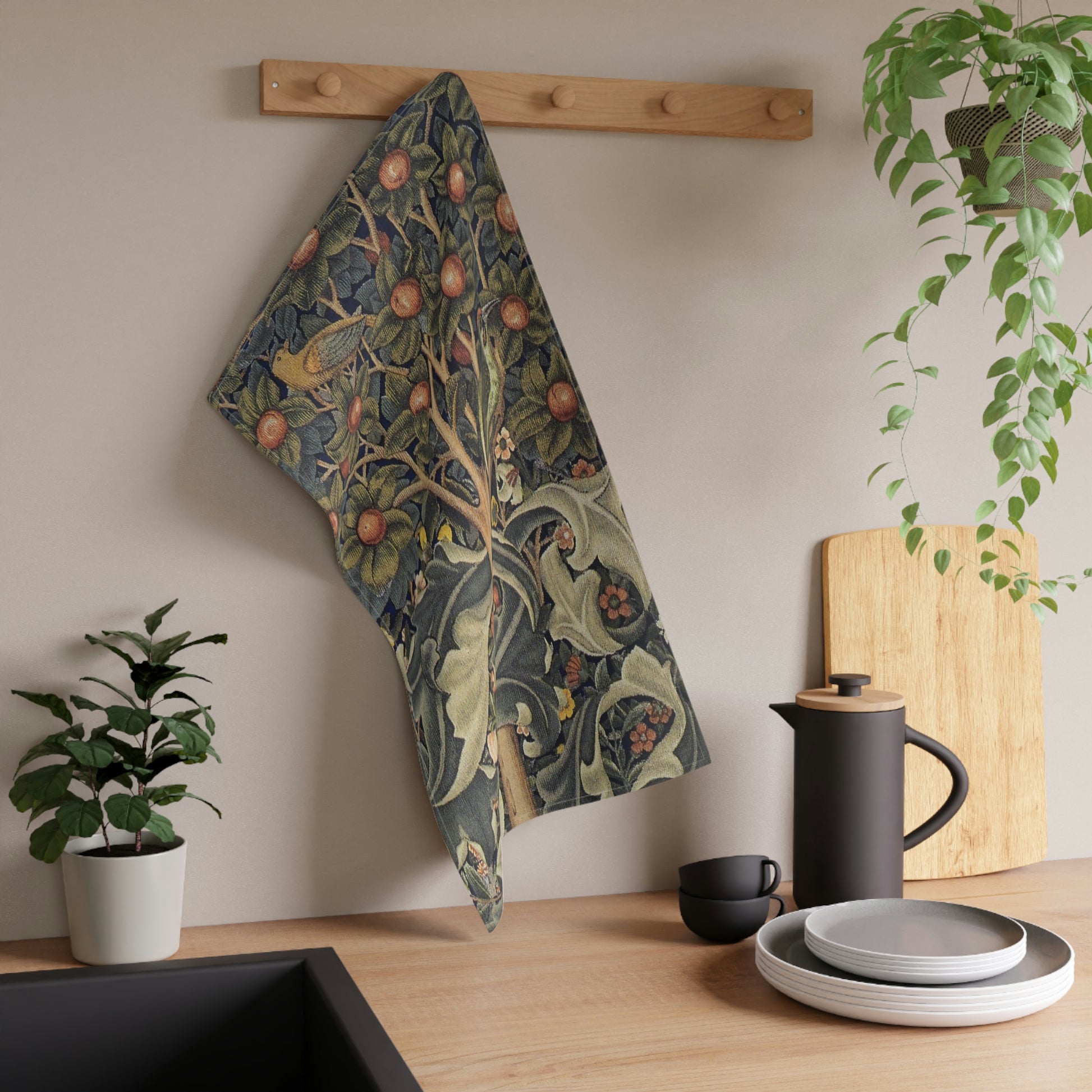 A kitchen tea towel featuring an artistic William Morris & Co design with birds, flowers, and leaves on a green background.
