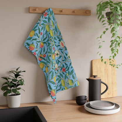 A kitchen tea towel with a blue background featuring a detailed floral and fruit pattern inspired by William Morris - Four Fruits Collection.