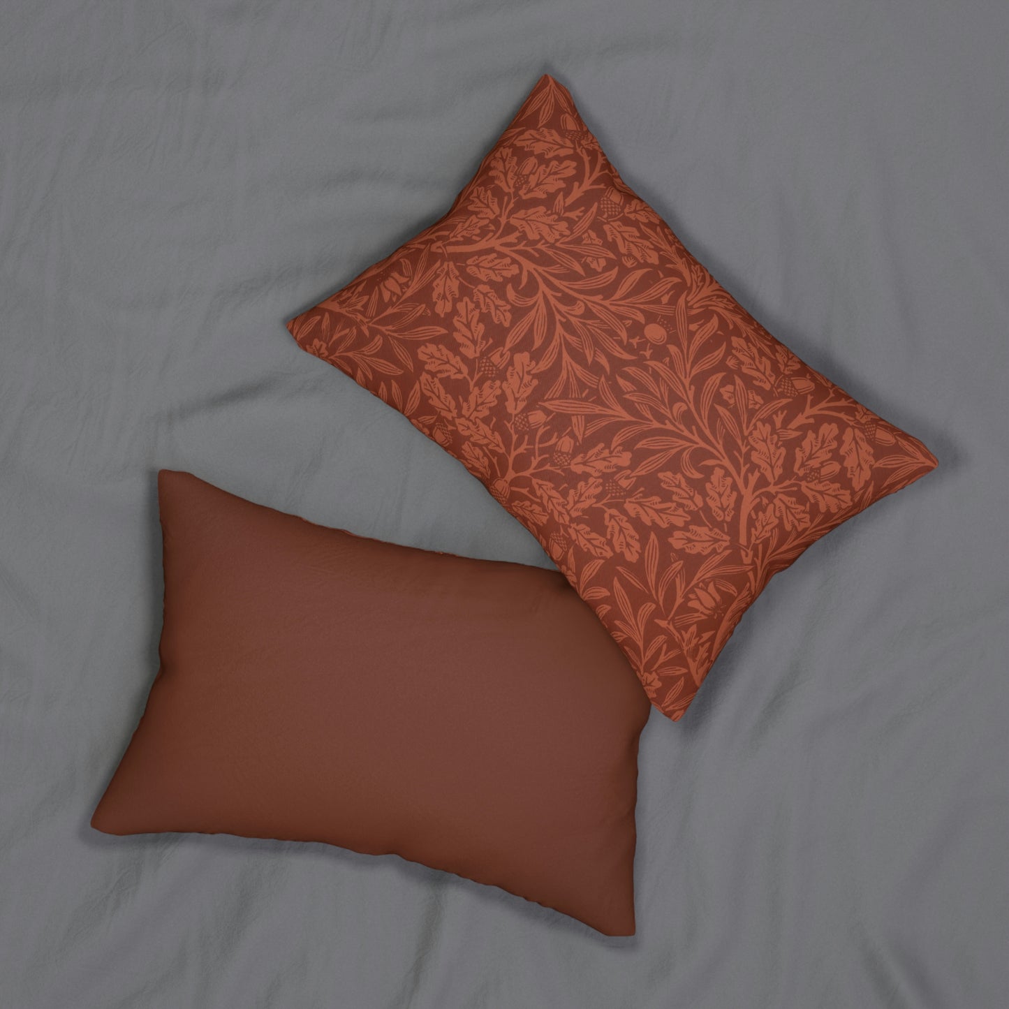 A rectangular lumbar cushion with a William Morris & CO floral pattern in a rust colour, featuring acorn and oak leaves, with a visible hidden zipper.