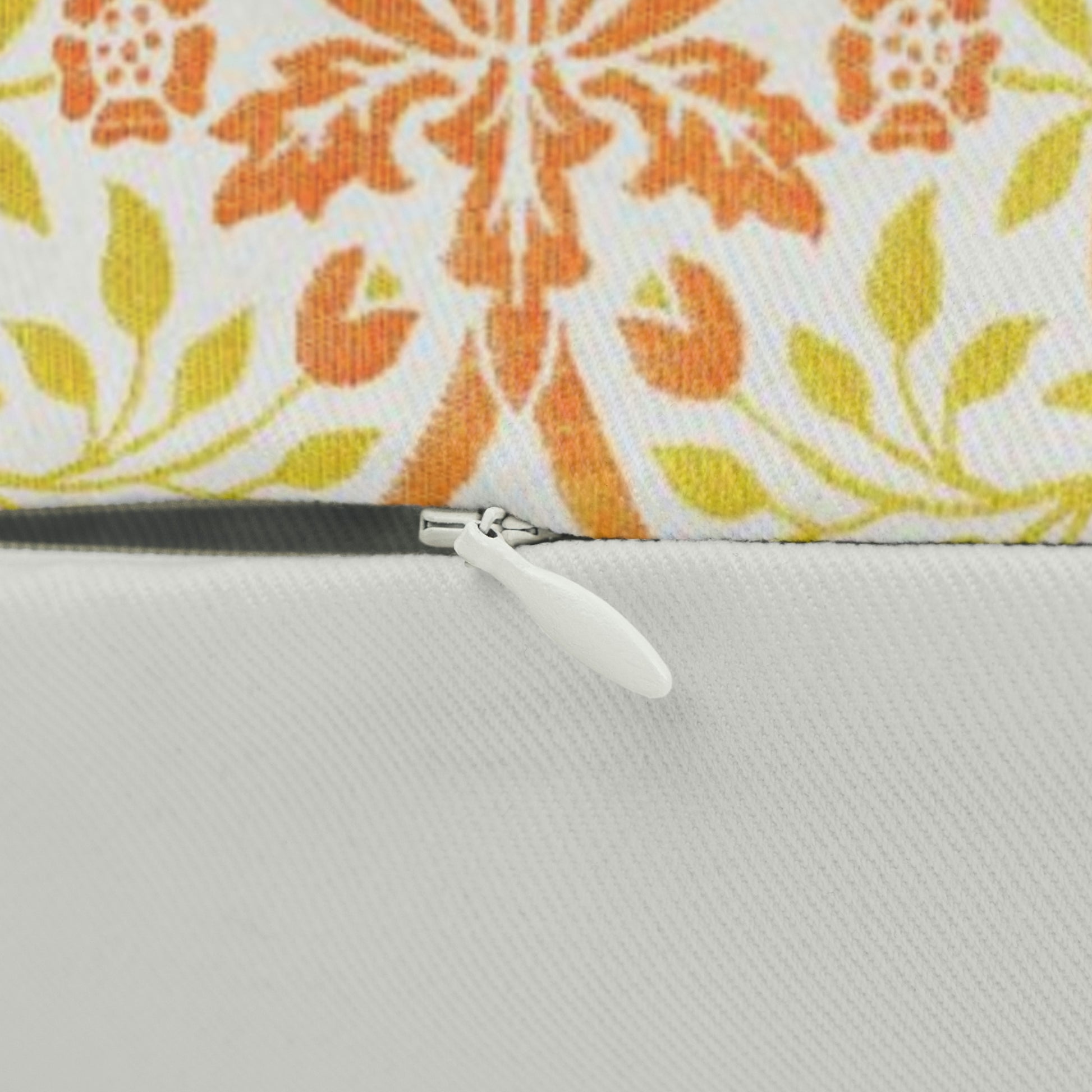 A rectangular lumbar cushion with a William Morris & Co floral pattern in shades of orange, beige, and yellow, featuring a concealed zipper.