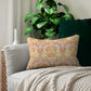 A rectangular lumbar cushion with a William Morris & Co floral pattern in shades of orange, beige, and yellow, featuring a concealed zipper.