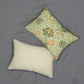 A rectangular lumbar cushion with a William Morris & Co floral pattern in green, beige, and orange colours, featuring a concealed zipper.