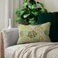 A rectangular lumbar cushion with a William Morris & Co floral pattern in green, beige, and orange colours, featuring a concealed zipper.