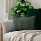 A rectangular lumbar cushion with a William Morris & Co floral pattern in shades of green and beige, featuring a concealed zipper.