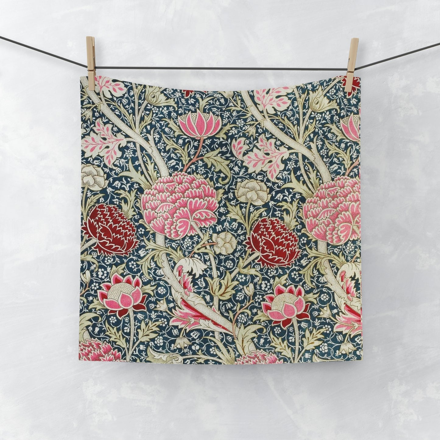 A white washcloth with a floral pattern inspired by William Morris, featuring vibrant colors on the front and a solid white back.