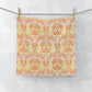 A white washcloth with a geometric floral pattern inspired by William Morris, featuring orange and yellow colours.