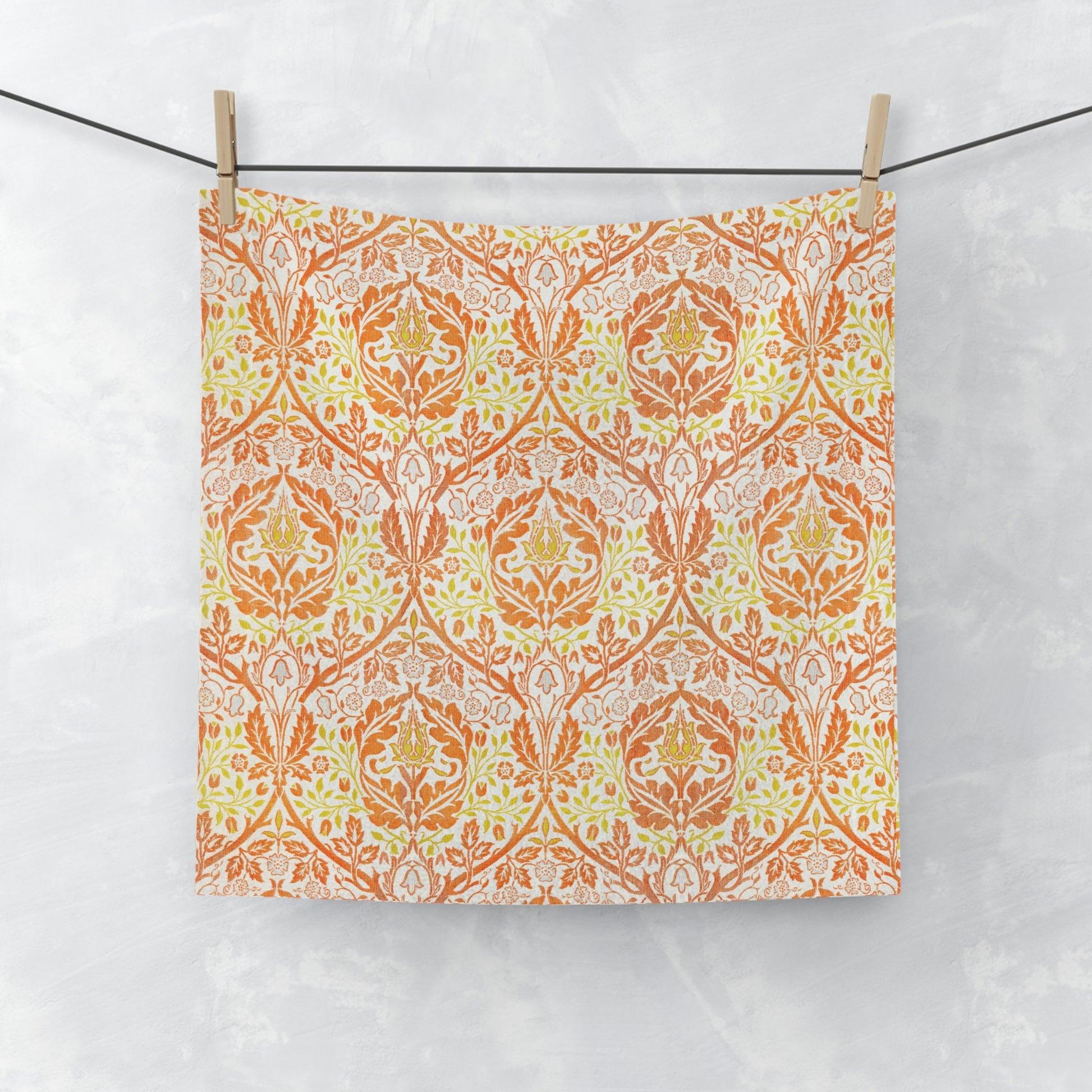 A white washcloth with a geometric floral pattern inspired by William Morris, featuring orange and yellow colours.