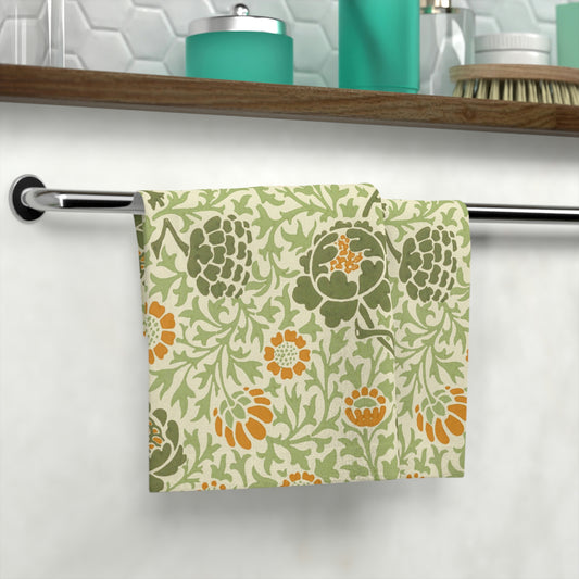 A white washcloth with a floral pattern inspired by William Morris, featuring green and orange colours.