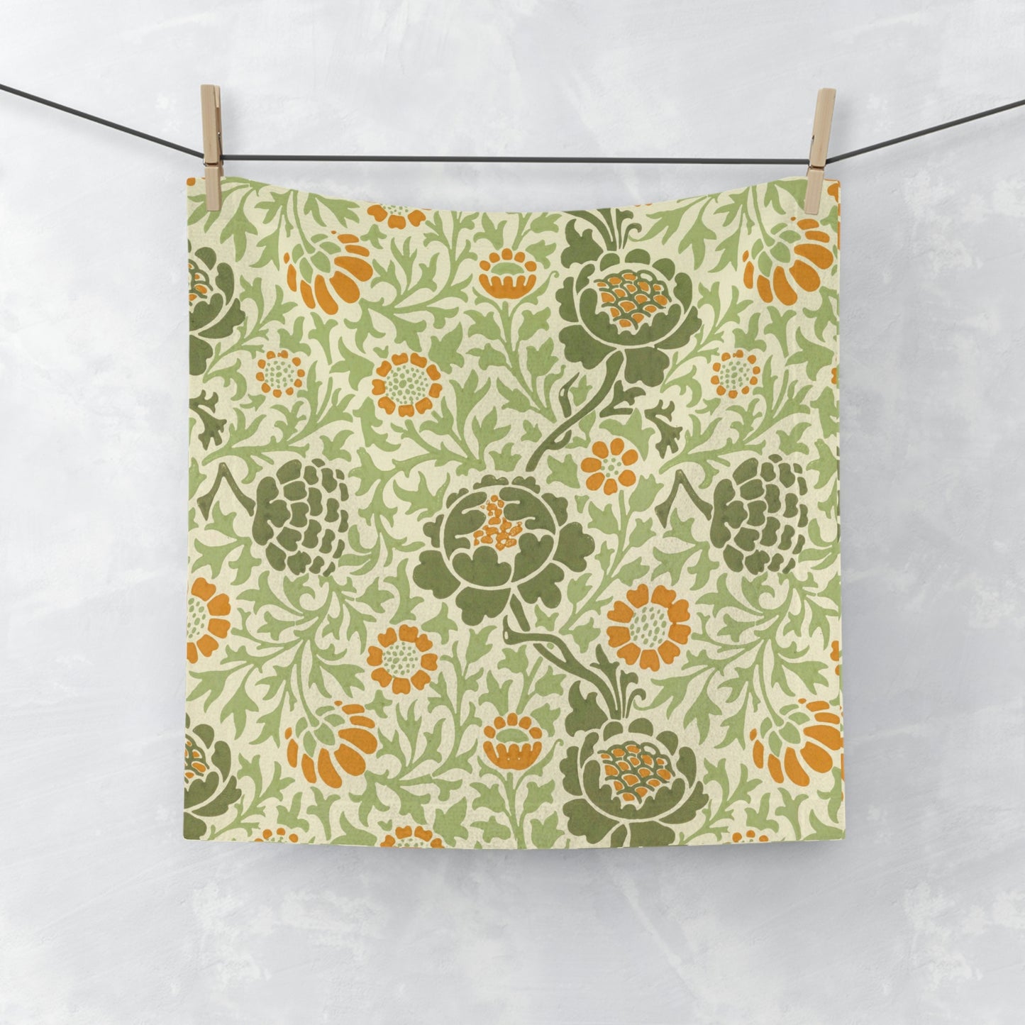 A white washcloth with a floral pattern inspired by William Morris, featuring green and orange colours.