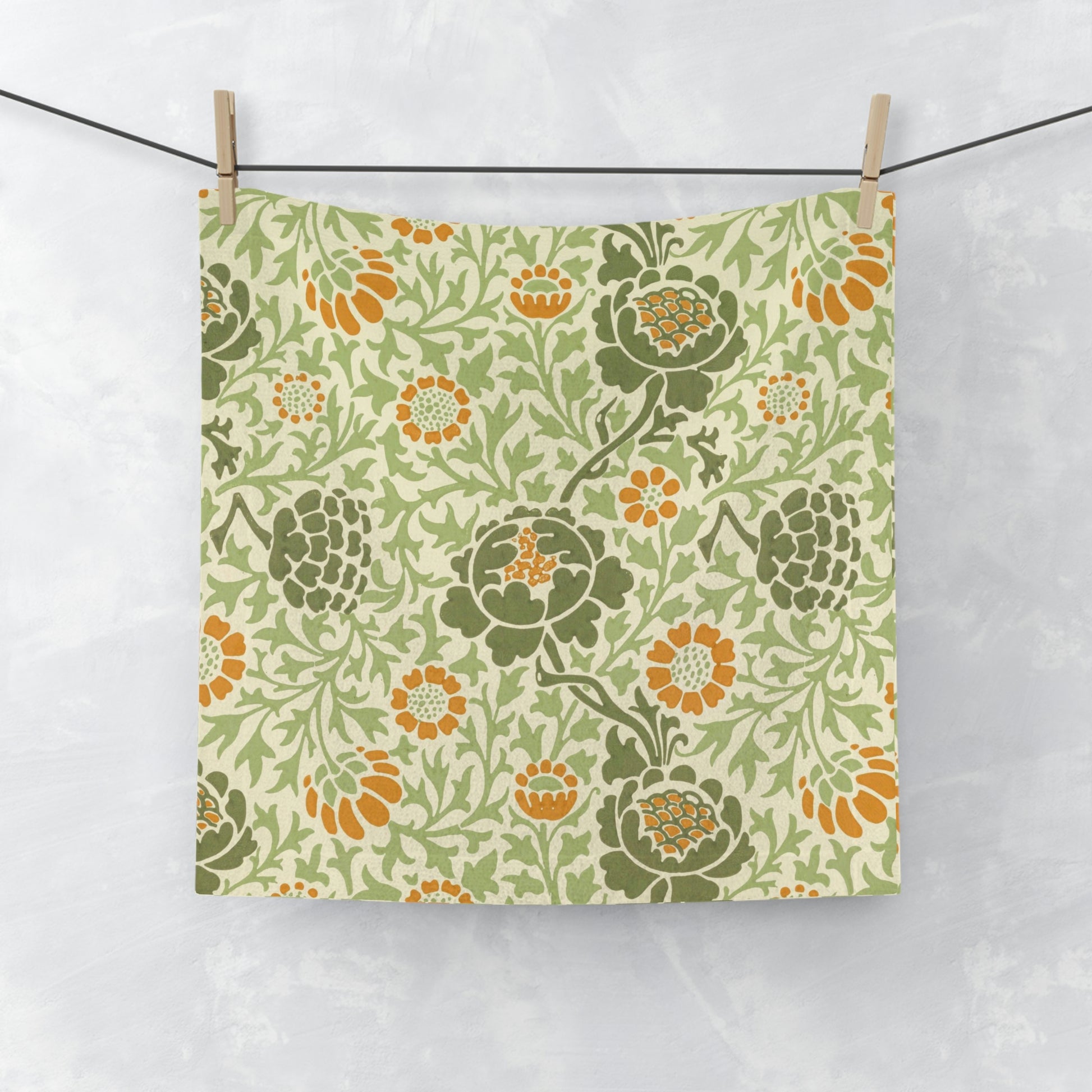 A white washcloth with a floral pattern inspired by William Morris, featuring green and orange colours.