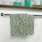 A white washcloth with a green floral pattern inspired by William Morris's art.