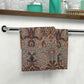 A white washcloth with a floral pattern inspired by William Morris, featuring a mix of colourful floral designs.