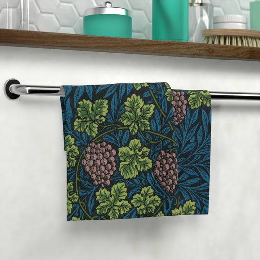 A white washcloth with a floral pattern inspired by William Morris, featuring green leaves and pink grapes.